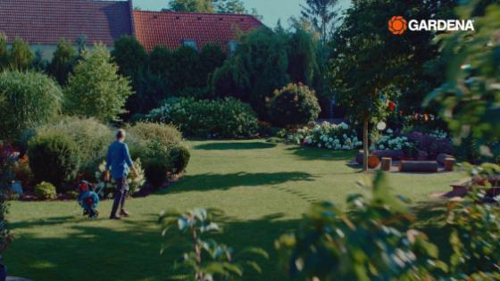 Uma pessoa no jardim com um carrinho de mangueira